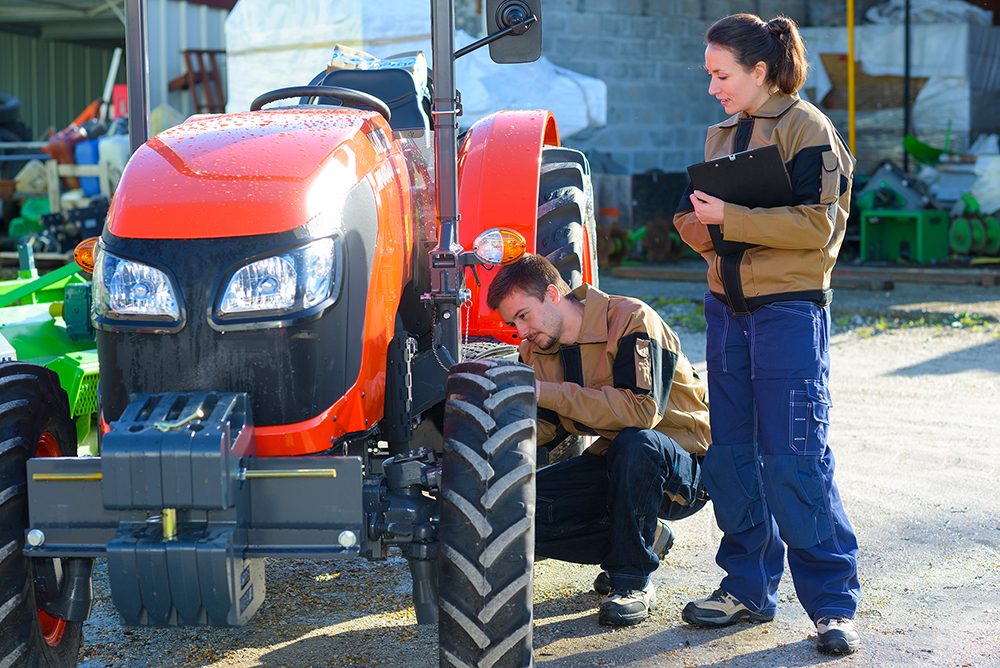 agricultural mechanics checking tractors condition before harvesting