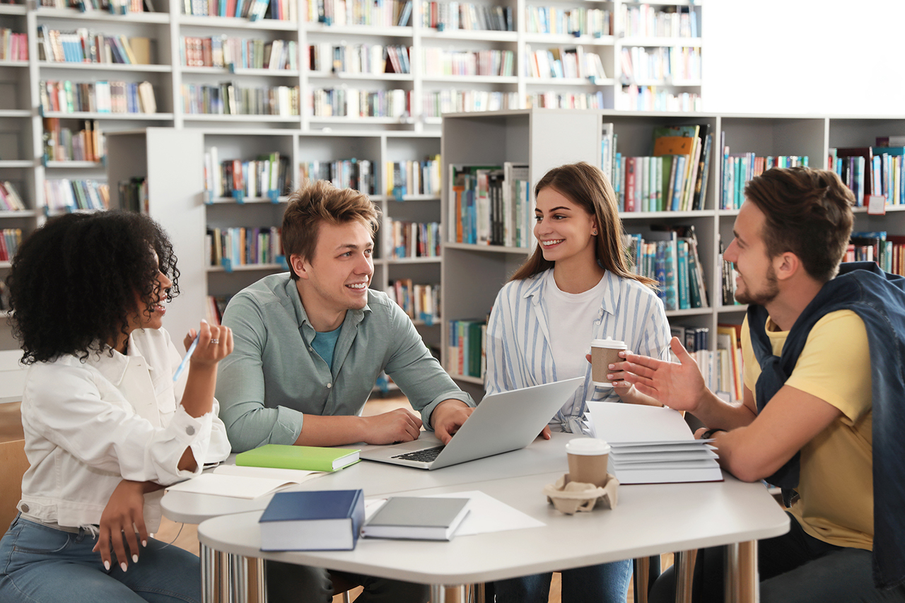 Group of young people studying at table in library