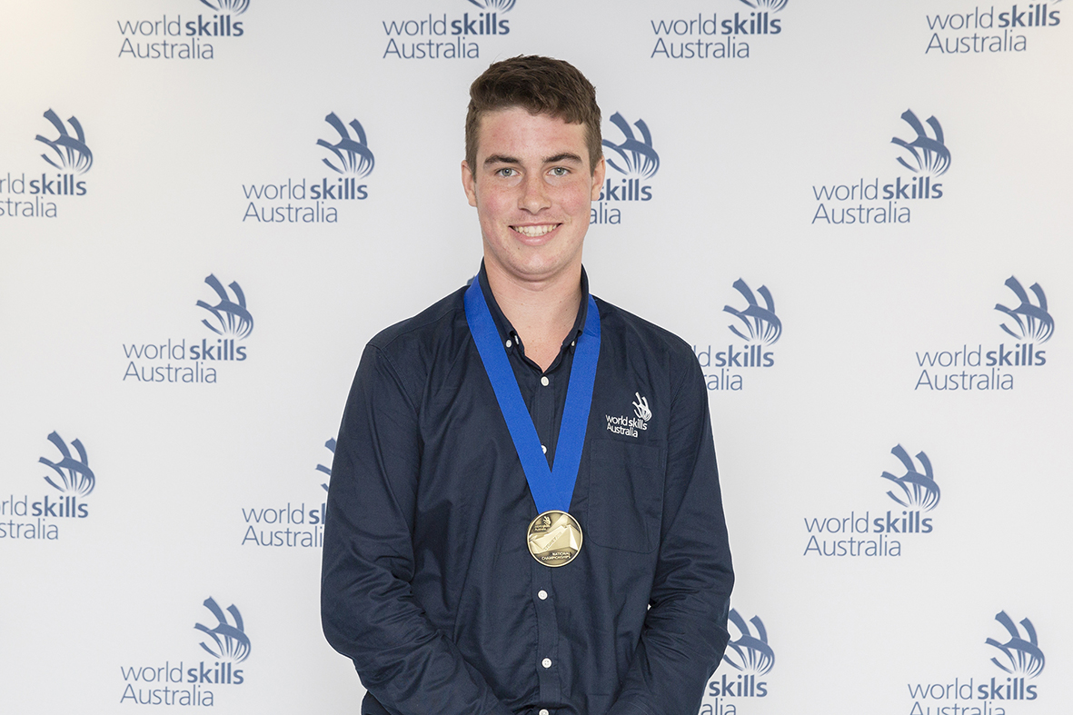 male student standing in front of world skills sign