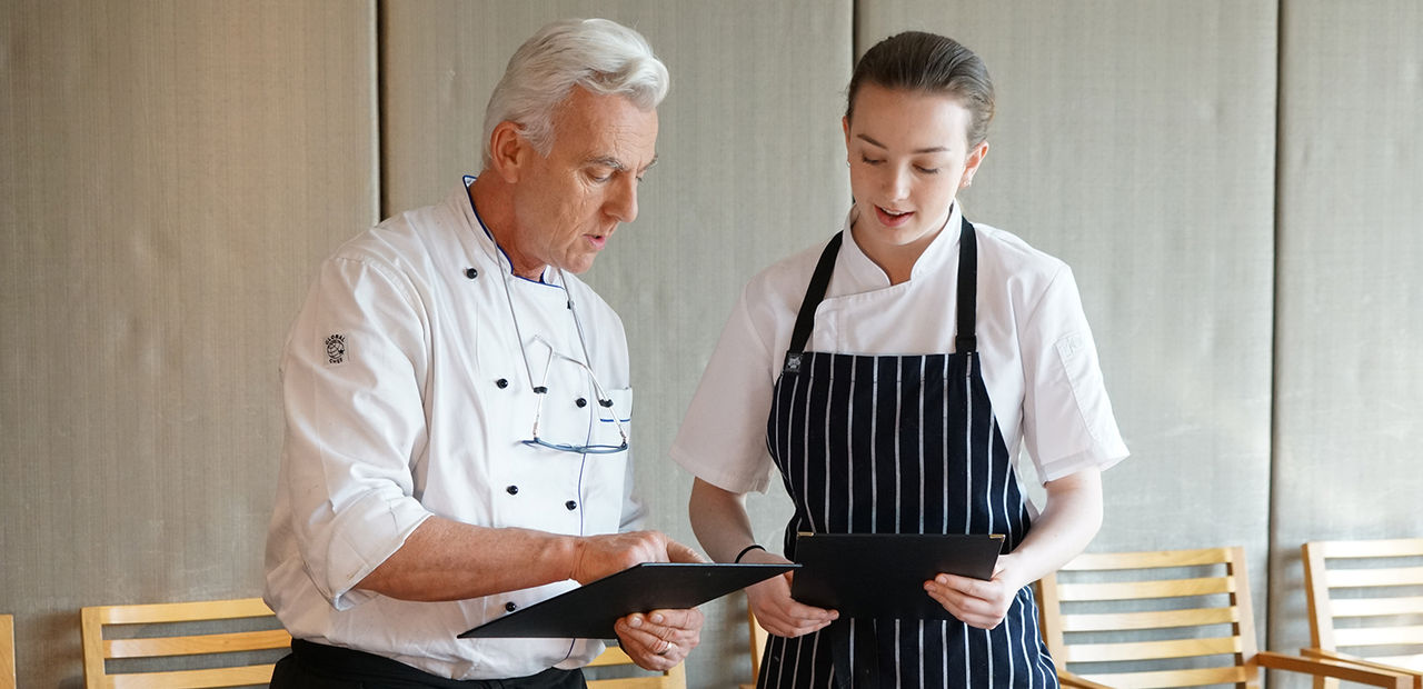 A cookery teacher and student discuss a menu