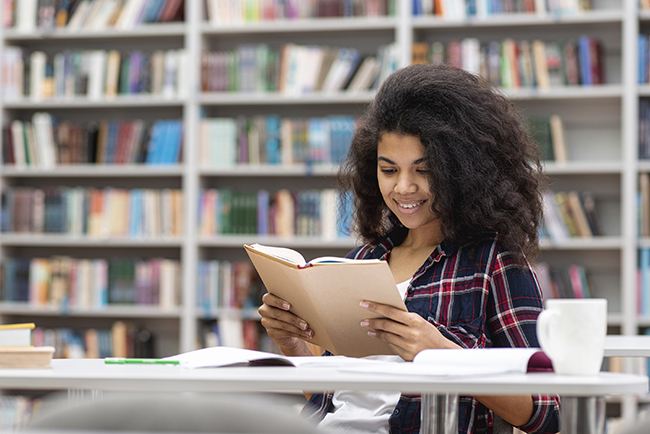 girl in library reading book